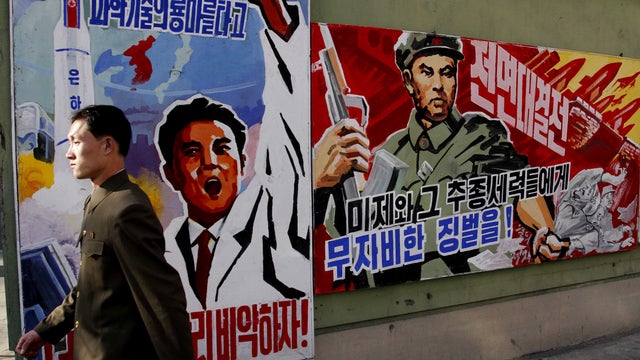 A North Korean man walks past propaganda posters in Pyongyang, North Korea, that threaten punishment to the "U.S. imperialists and their allies." 