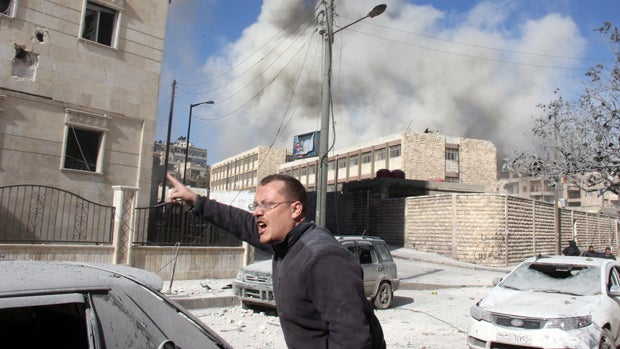 A man reacts as smoke billows following an alleged airstrike by Syrian government forces Jan. 31, 2014, in the northern Syrian city of Aleppo. 