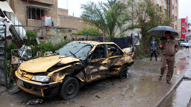 Iraqis inspect the site of a car bomb in a commercial area in the Hurriyah neighborhood of northern Baghdad 