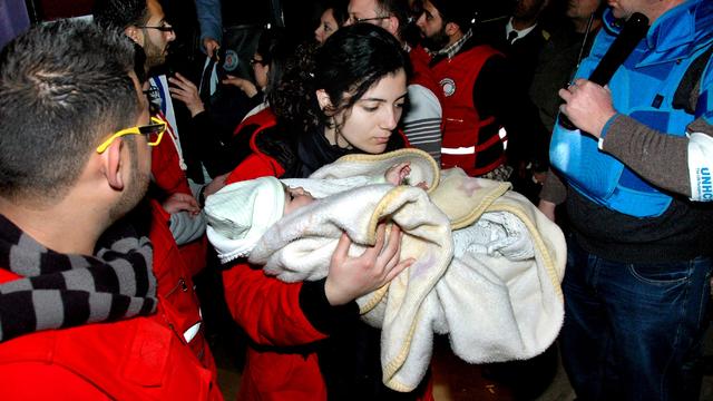 A Syrian Arab Red Crescent member carries a baby to a bus to evacuate the battleground city of Homs, Syria.  