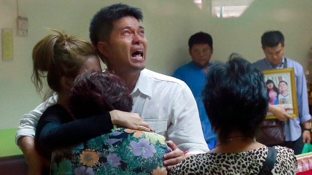 Tayakorn Yos-ubon, the father of two children killed in a bomb attack on an anti-government protest site, is embraced by his family 