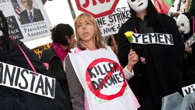 Medea Benjamin (C), and other activists hold signs during a rally against U.S. drone attacks in front of the White House 