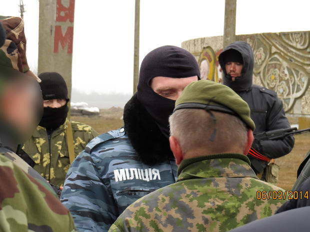 Two members of an Organisation for Security and Cooperation in Europe (OSCE) military observer mission (facing away from camera) are stopped at the Crimean border by unknonw armed men 