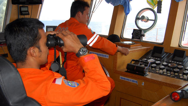 A member of Indonesian National Search And Rescue Agency (BASARNAS) uses binoculars to scan the horizon during a search operation for the missing Malaysia Airlines Boeing 777 