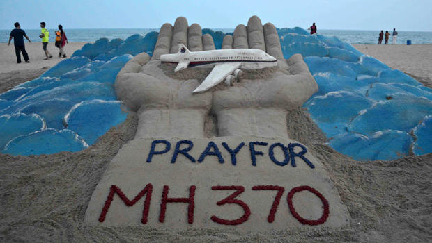 Beachgoers walk past a sand sculpture made by Indian sand artist Sudersan Pattnaik with a message of prayers for the missing Malaysian Airlines Flight MH370 at Puri beach in India March 12, 2014. 