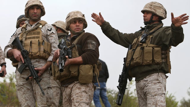 A Lebanese army officer from a commando unit, right, gives orders to his soldiers after they blew up a bomb-packed parked car in a field outside the village of Fakiha, near the Lebanese and Syria border 