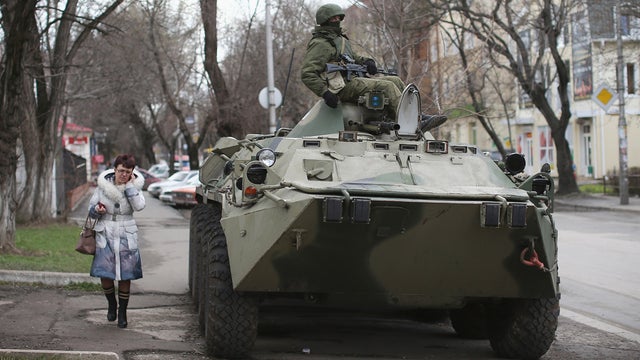 A woman walks past a Russian military personnel carrier outside a Ukrainian military base 