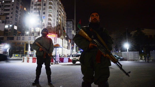 Afghan policemen block a road near the security perimeter set up around the Serena hotel 