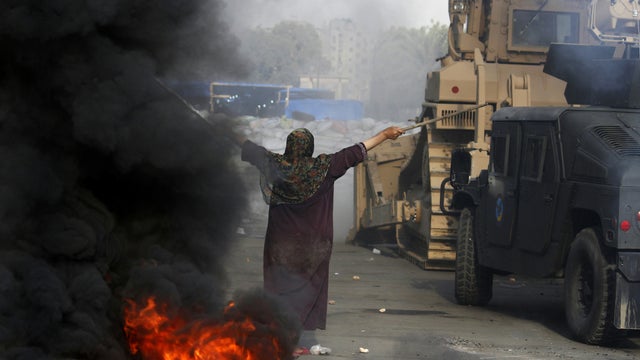 An Egyptian woman tries to stop a military bulldozer from going forward during clashes that broke out as Egyptian security forces moved in to disperse supporters of Egypt's deposed president Mohamed Morsi  