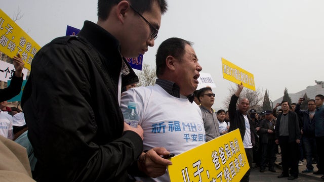 Wen Wanchang, whose son was on board the missing Malaysia Airlines plane, holds a placard as he protests outside the Malaysian Embassy in Beijing 