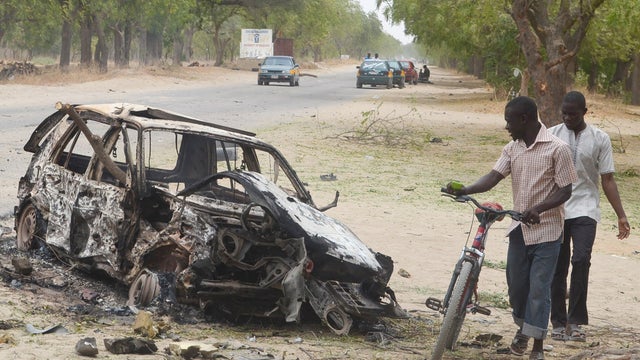 People inspect the remains of a car used in a suicide bomb in Nigeria 