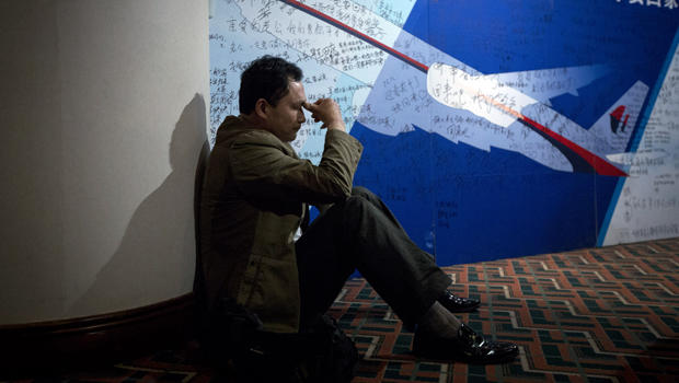 A man, one of the relatives of Chinese passengers onboard Malaysia Airlines Flight 370, rests near a board covered with written wishes at a hotel in Beijing March 29, 2014. 
