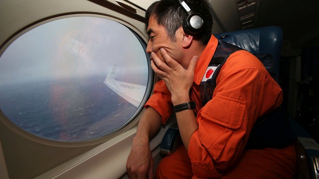 Koji Kubota of the Japan Coast Guard keeps watch through a window of a Gulfstream V aircraft in the search zone for the missing Malaysia Airlines flight MH370 