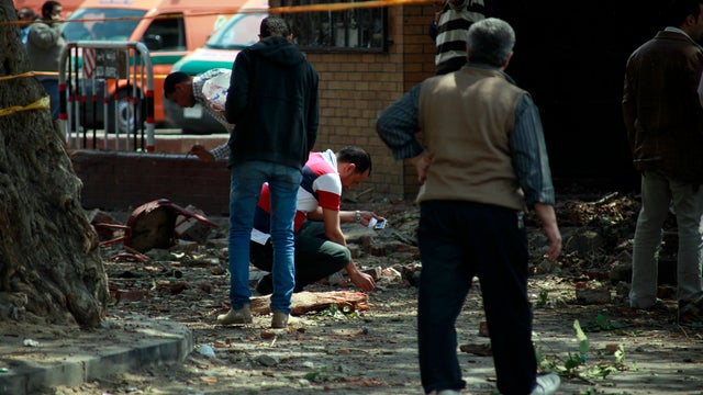 Egyptian security forces inspect the site after multiple explosions hit the area outside the main campus of Cairo University 