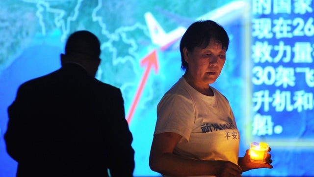 A Chinese relative of passengers on missing Malaysia Airlines flight 370 holds candle as she takes part in prayer service at Metro Park Hotel in Beijing on April 8, 2014  
