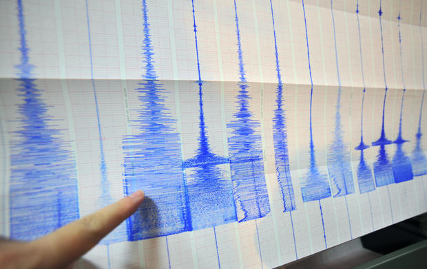 A man points at a seismic chart at the C 