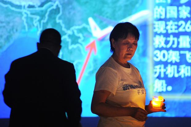 A Chinese relative (R) of passengers on the missing Malaysia Airlines flight MH370 holds a candle as she takes part in a prayer service at the Metro Park Hotel in Beijing 