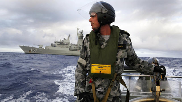 Standing in a rigid hull inflatable boat launched from the Australian navy ship HMAS Perth, Leading Seaman, Boatswain's Mate, William Sharkey searches for possible debris in the southern Indian Ocean in the continuing search for the missing Malaysia Airli 