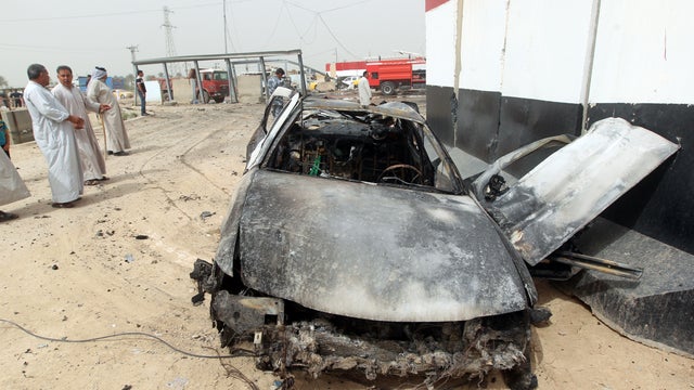 Iraqis gather at the scene of a car bomb explosion at a checkpoint in the Suweirah area, south of Baghdad 