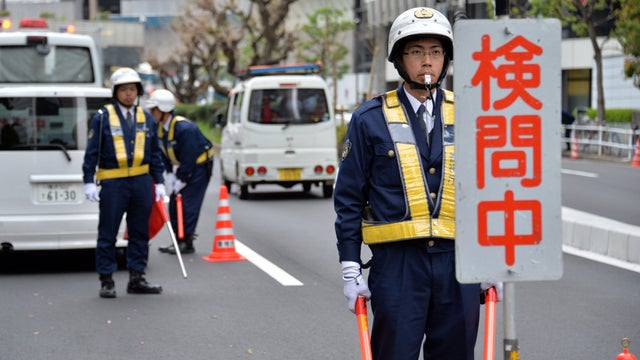 Police officers check a vehicles at a checkpoint near the U.S. Embassy in Tokyo, the day before  President Obama arrives  