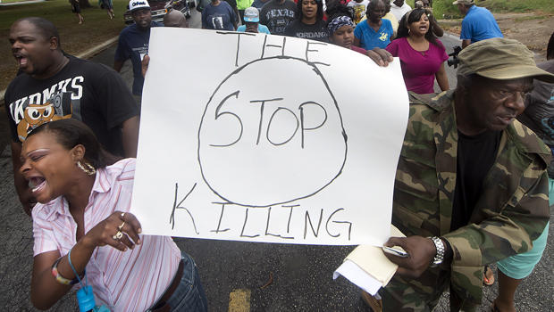 K.K. Davis, left, and Tommy Jones of Hearne, Texas, carry a sign with other protesters outside the Hearne Police Department May 8, 2014, following the shooting two days earlier of a 93-year-old woman. 