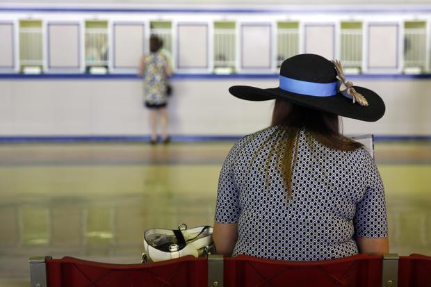 A woman in a hat sits in front of the betting windows before the 139th Preakness Stakes at Pimlico Race Course in Baltimore May 17, 2014. 