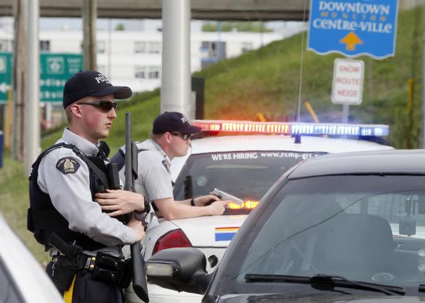 Armed Royal Canadian Mounted Police (RCMP) officers guard exit ramp during hunt for Justin Bourque, who allegedly shot 3 police officers dead and wounded 2 more in Moncton 