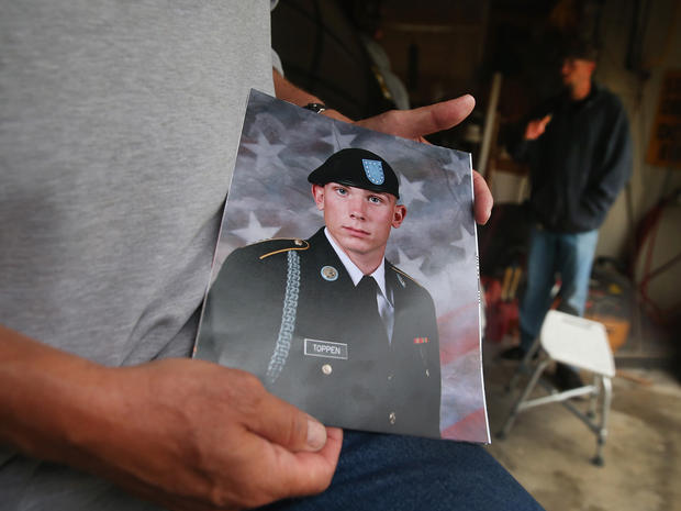 Jack Winter holds a picture of his nephew Aaron Toppen as family and friends gather to grieve at Toppen's mother's home 
