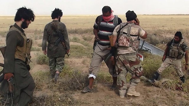 ​Militants of the Islamic State of Iraq and Syria (ISIS) hold an apparent member of the Iraqi security forces captive in an unverified image published on the Sunni militant group's website 