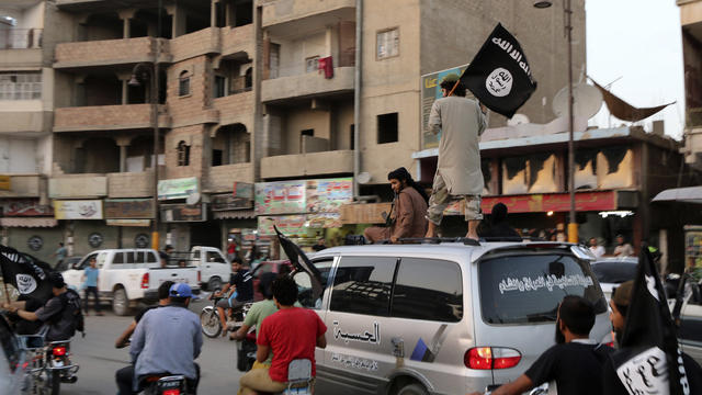 Members loyal to ISIS wave ISIS flags as they drive around Raqqa, Syria on June 29, 2014 