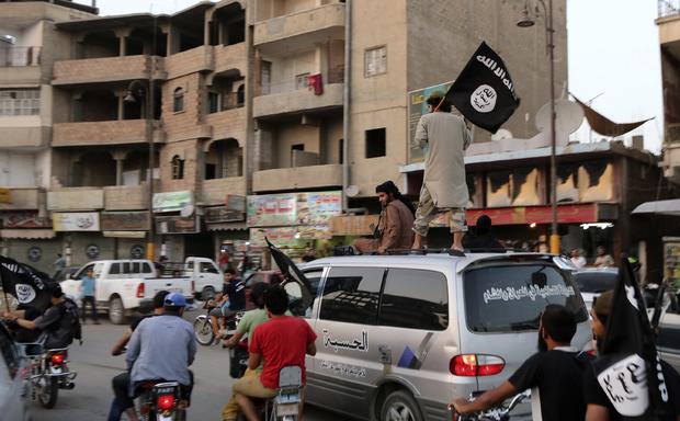 ISIS loyalists wave ISIS flags as they drive around Syrian city of Raqqa on June 29, 2014 