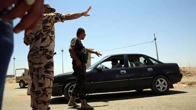 A Kurdish Peshmerga soldier turn back cars at a check-point as thousands of Iraqis who have fled fighting in Mosul and Tal Afar try to enter a temporary displacement camp 