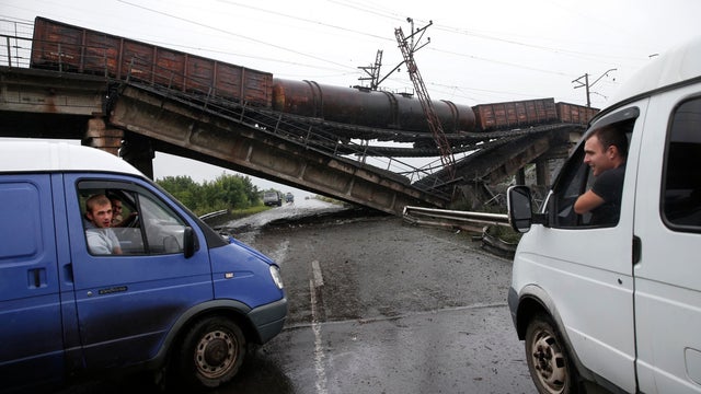 Drivers chat from their vehicles near a destroyed railroad bridge which collapsed onto a main road leading to the eastern Ukrainian city of Donetsk 