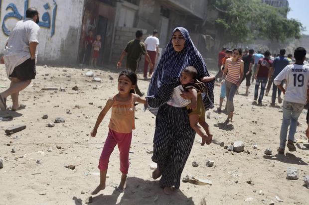 A Palestinian woman runs with her children following what police said was an Israeli airstrike 