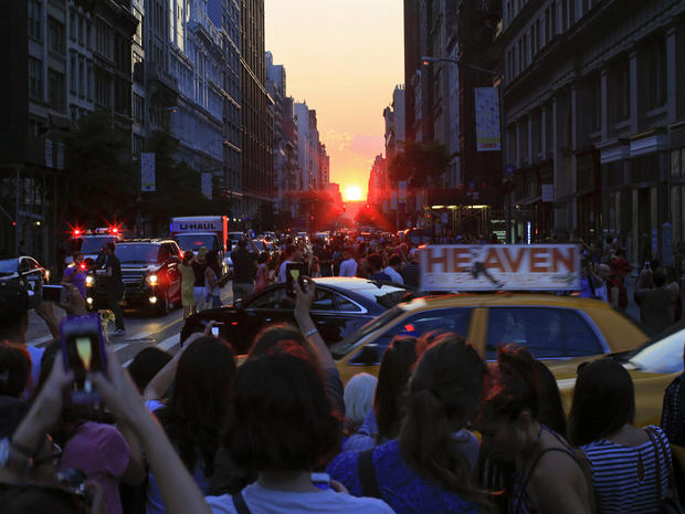 People take pictures at sunset during the bi-annual occurrence of Manhattanhenge in New York July 11, 2014. 