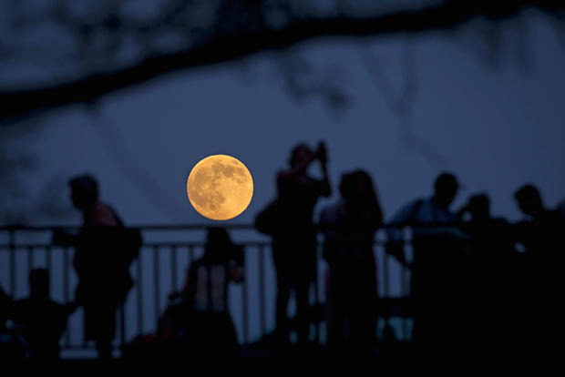 People stand and look at the moon one day ahead of the Supermoon phenomenon from a bridge over 42nd Street in the Manhattan borough of New York July 11, 2014. 