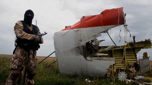 A pro-Russian rebel fighter stands next to a large piece of wreckage from Malaysia Airlines Flight 17 