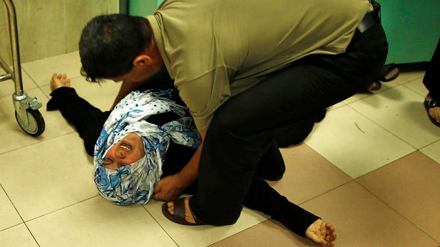 A Palestinian mother lies on the ground as she mourns the death of her son, who medics said was killed by Israeli shelling 