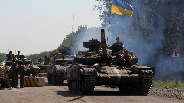 Ukrainian army tanks move past a checkpoint as they patrol the area near eastern Ukrainian town of Debaltseve 
