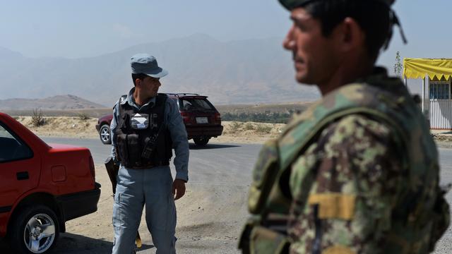 An Afghan National Army (ANA) soldier (R) and a policeman keep watch at a checkpoint near the Marshal Fahim National Defense University, a training complex on the outskirts of Kabul 