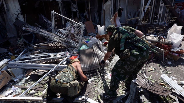 Armed pro-Russian separatists inspect wreckage near a damaged building following what locals say was an airstrike by Ukrainian forces in Donetsk 