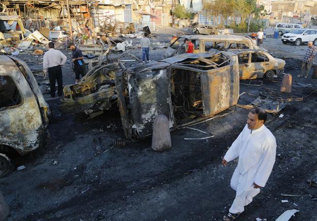 Man walks past the site of a car bomb attack in Baghdad's Sadr City 