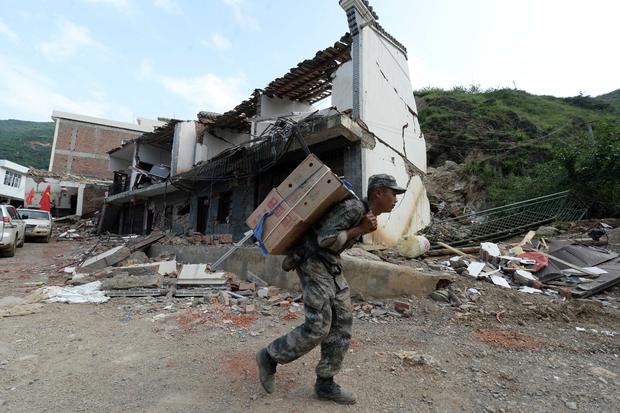 A rescue worker carries relief supplies to a remote village in disaster-hit Ludian county in Zhaotong, southwest China 