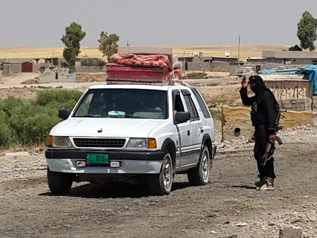A fighter with ISIS directs a vehicle with a Christian family to leave from their home village outside Erbil 