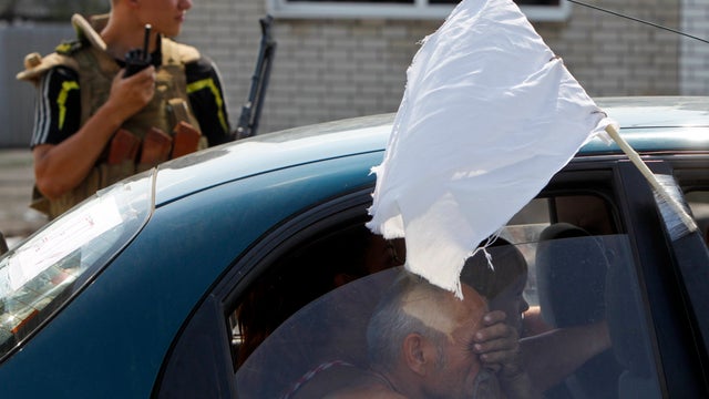 Refugees from the city of Luhansk sit inside a car at a checkpoint near the eastern Ukrainian town of Debaltseve 