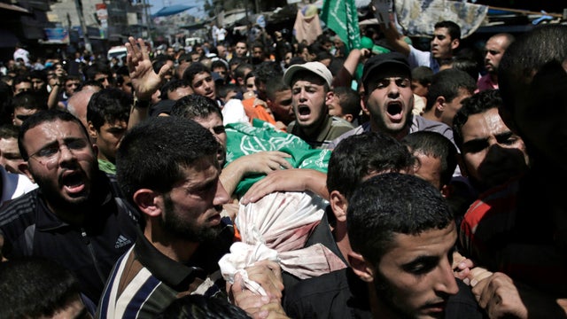Palestinian mourners chant angry slogans as they carry the body of Mohammed Abu Shamaleh, one of three senior commanders of the Hamas military wing who were killed in Israeli strikes 