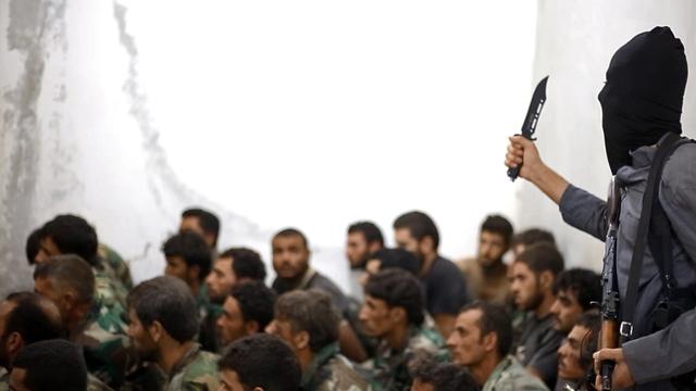 A fighter from the Islamic State of Iraq and Syria, or ISIS, is seen armed with a knife and an automatic weapon next to captured Syrian army soldiers and officers following the battle for the Tabqa air base, in Raqqa, Syria, in this undated image. 