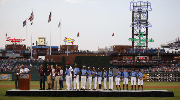 Members of the Taney Dragons baseball team listen to Philadelphia Mayor Michael Nutter speak during a tribute to celebrate the youth team's accomplishments before a baseball game between the Philadelphia Phillies and the Washington Nationals Aug. 27, 2014, in Philadelphia. 