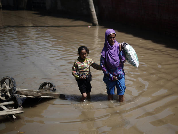 A Kashmiri woman and her daughter wade through a flooded street in Srinagar 
