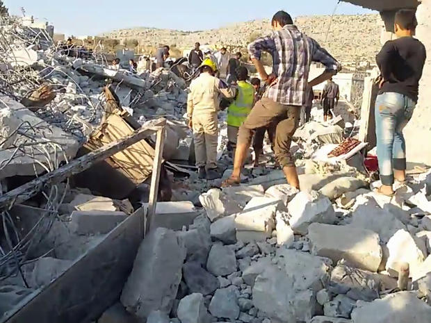 An image taken from video posted by Syrian activists shows residents and rescue workers sifting through rubble after apparent U.S. airstrikes in Kfar Daryan, Idlib province 